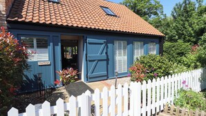 A blue building with a tiled roof, a white picket fence, and a sign reading "The Forge".