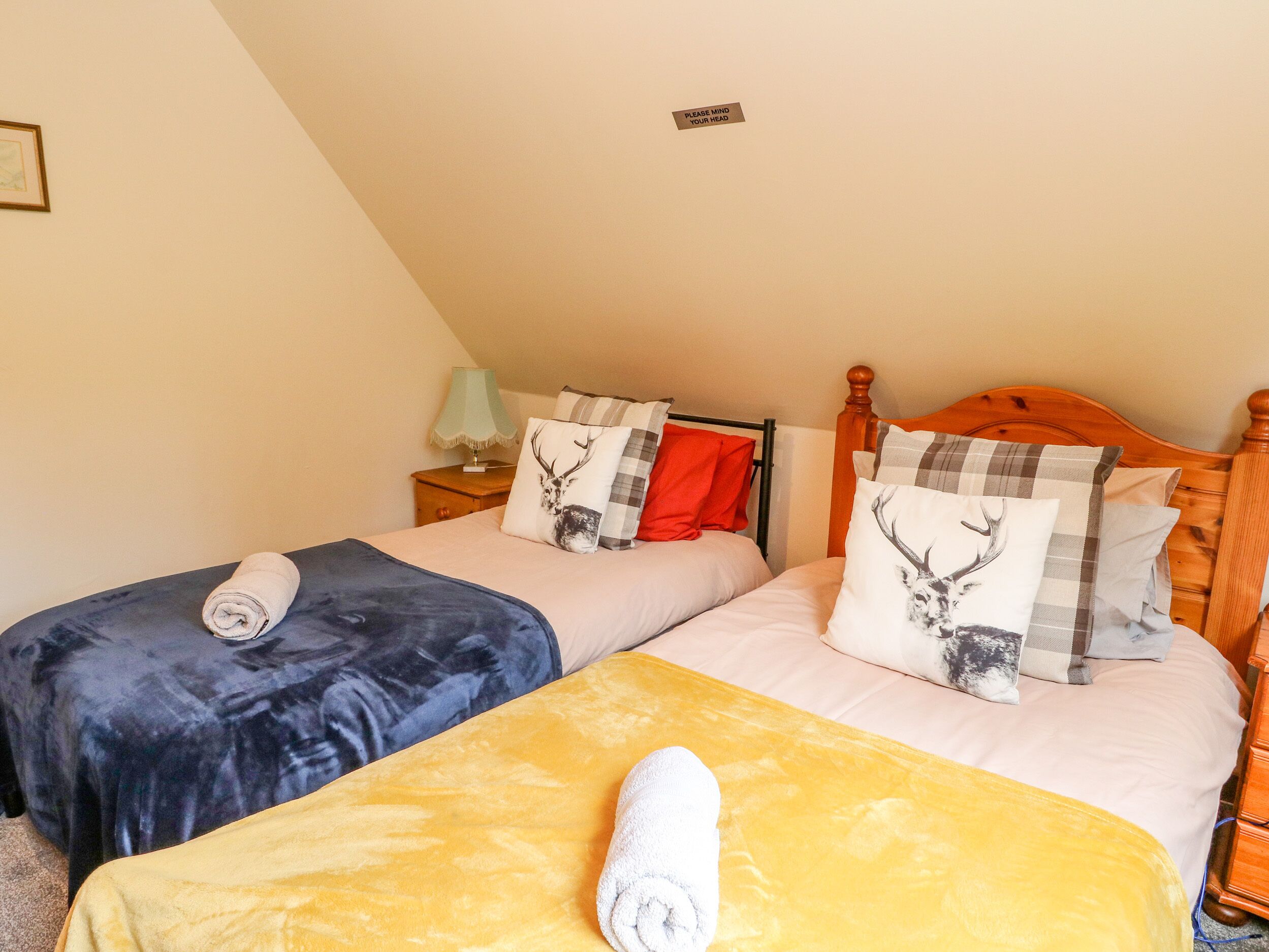 Un dormitorio con dos camas, cada una con un edredón de diferente color, una mesita de noche con lámpara y un letrero en la pared.