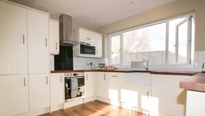 Une cuisine moderne avec des armoires blanches, une hotte de cuisinière en acier inoxydable, un four et un four à micro-ondes.