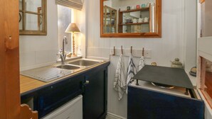 Een kleine keuken met een spoelbak, een fornuis en een spiegel boven het aanrecht.