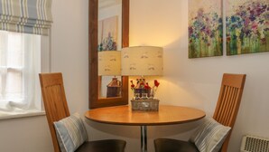 Een eetruimte met een ronde tafel, twee stoelen, een spiegel en decoratie aan de muur.