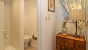 Een badkamer met een douche, toilet en een houten kast met lades.