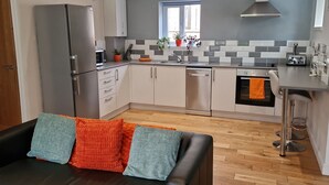 Una cocina moderna con armarios blancos, un refrigerador de acero inoxidable, un lavavajillas y una ventana sobre el fregadero.