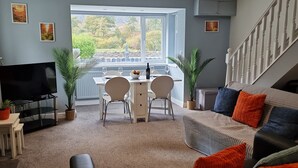 Una sala de estar moderna con comedor, televisor y escalera.