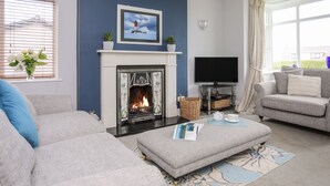 A living room with a fireplace, a television, and a sofa. - Bryngwyn - Trearddur Bay (Holyhead)