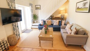 A living room with a sofa, a coffee table, a TV, and a staircase.