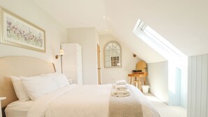 A bedroom with a bed, a nightstand, a dresser, a mirror, and a window.