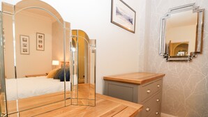 A bedroom with a bed, bedside table, dresser, and mirrors. - Tethera (Windermere)