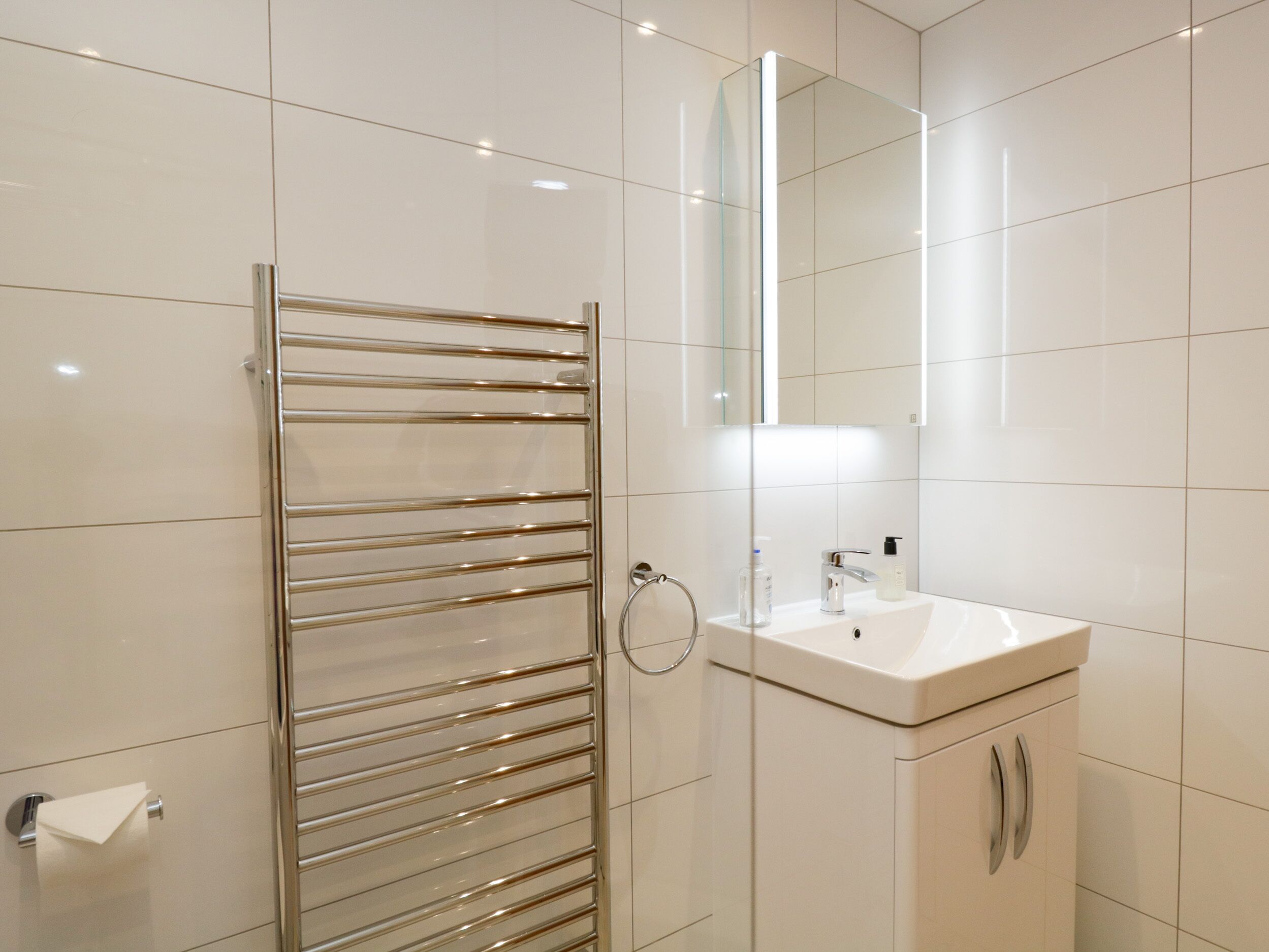 Un baño moderno con cabina de ducha de vidrio, un lavabo blanco y un espejo sobre él.
