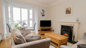 A living room with a sofa, a coffee table, a TV, and a fireplace. - Tethera (Windermere)