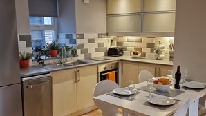 Una cocina moderna con horno empotrado, un fregadero y una zona de comedor con mesa y sillas.