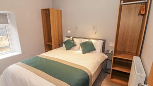 Un dormitorio ordenado con cama, mesitas de noche, armario y radiador.