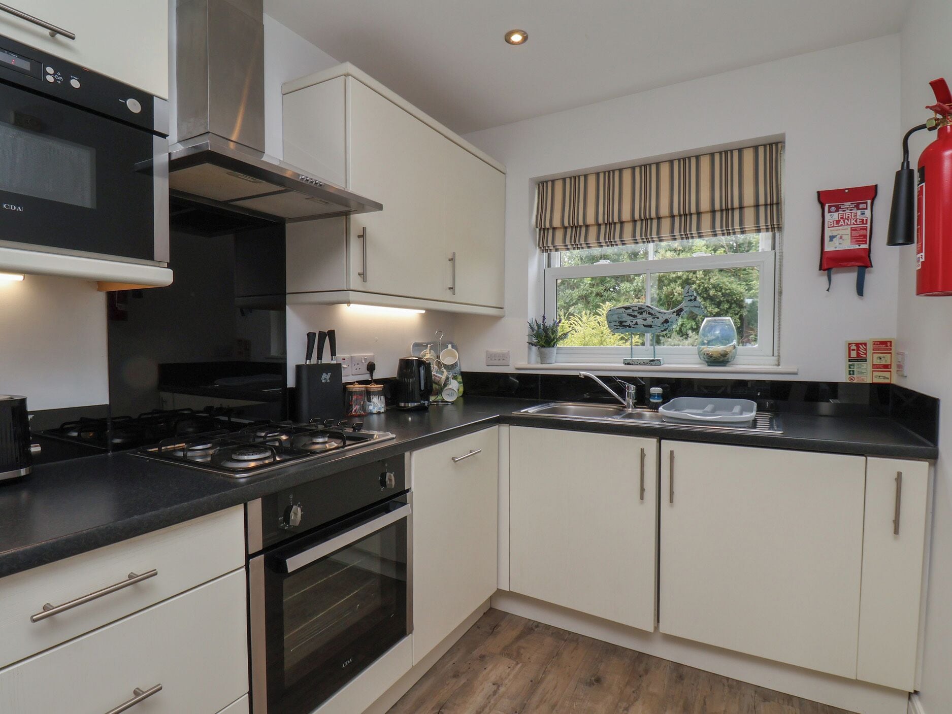 A modern kitchen with white cabinets, a black countertop, and stainless steel appliances.
