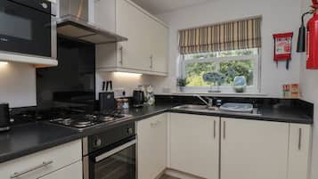 A modern kitchen with white cabinets, a black countertop, and stainless steel appliances.