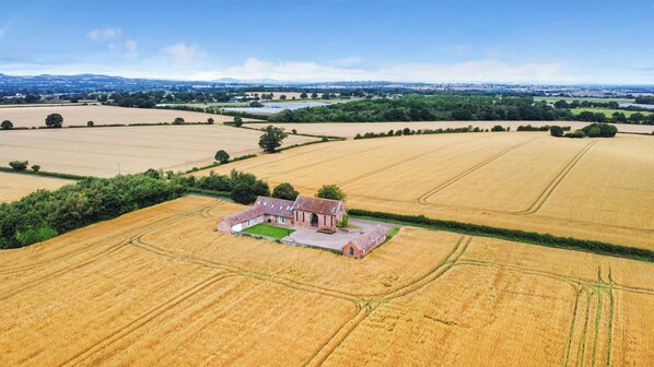 An aerial view of a rural property with fields, a farmhouse, and surrounding greenery.