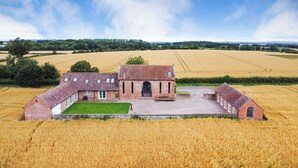A large, historic brick building with multiple rooms and a central courtyard, surrounded by expansive fields. - Windy Mundy Farm at Pitchford Estate (Shrewsbury)