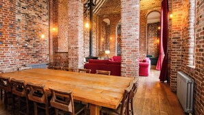 A spacious room with a large wooden table and chairs, brick walls, and a red sofa. - Windy Mundy Farm at Pitchford Estate (Shrewsbury)
