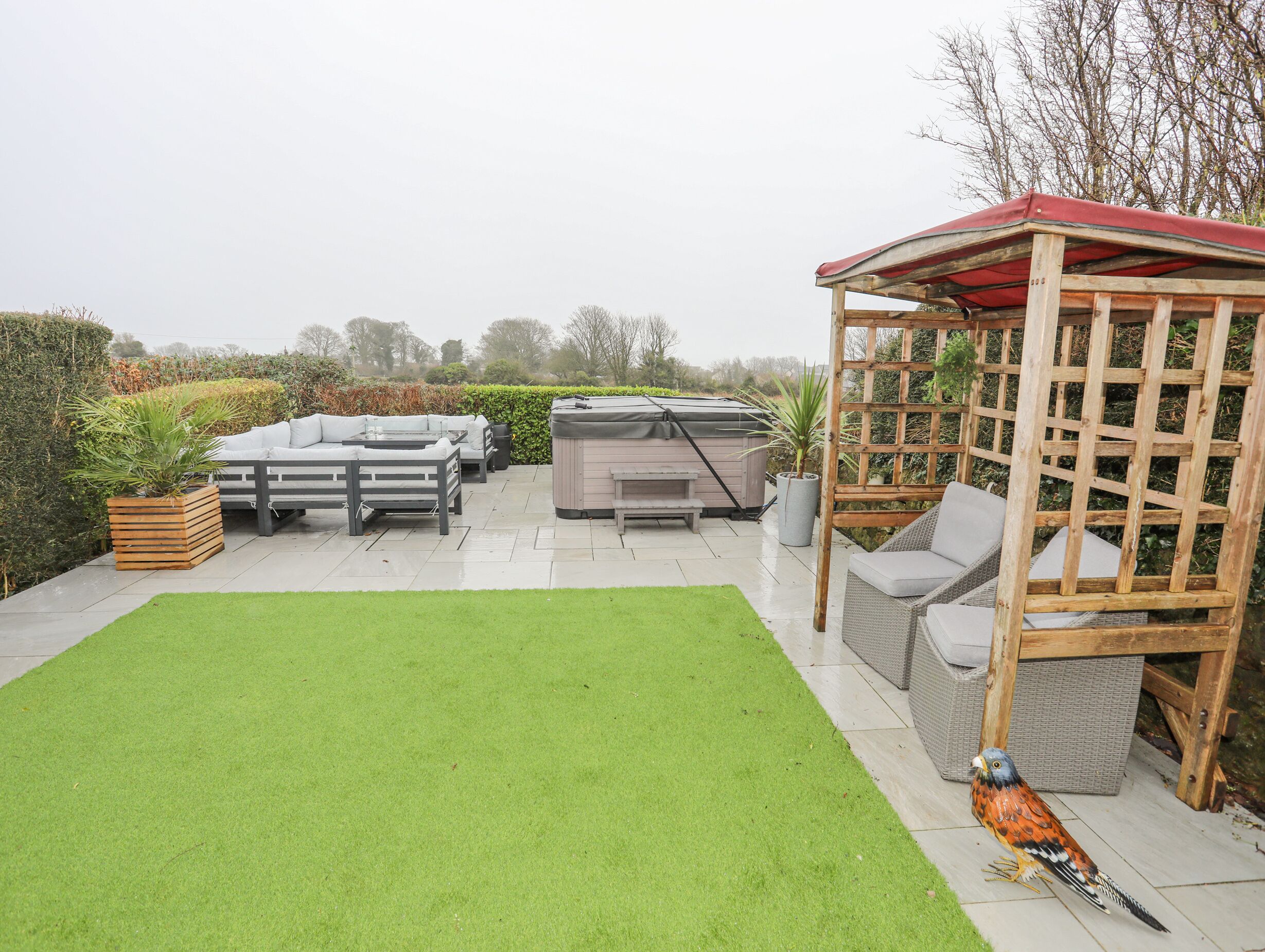 A patio area with a hot tub, outdoor furniture, and a wooden pergola.