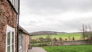 Un bâtiment en pierre avec un chemin de gravier menant à un champ verdoyant.