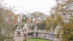 Un bâtiment de style Tudor, doté d’une façade symétrique, de nombreuses cheminées et d’un jardin bien entretenu.