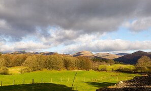 A rural landscape with rolling hills, a fenced field, and a clear sky. - Honister Cottage (Ambleside)