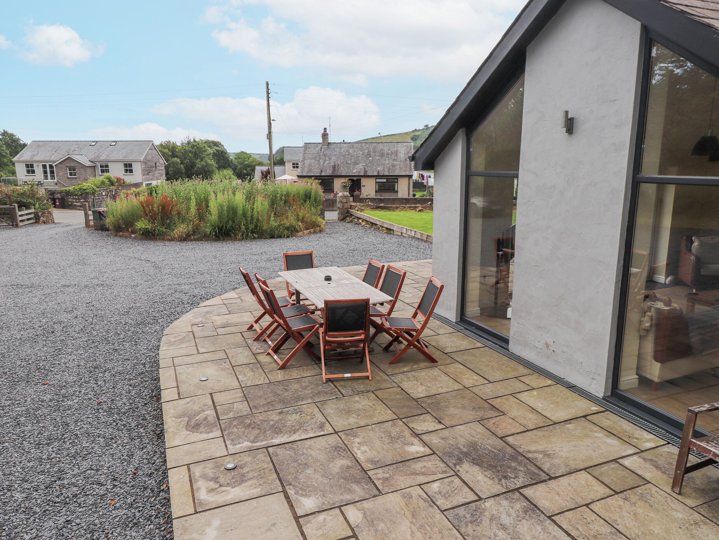 A patio area with a table and chairs, surrounded by a gravel path and a garden.