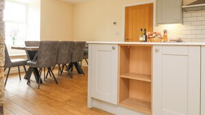 A kitchen with white cabinets, a wooden countertop, and a dining area with a table and chairs.
