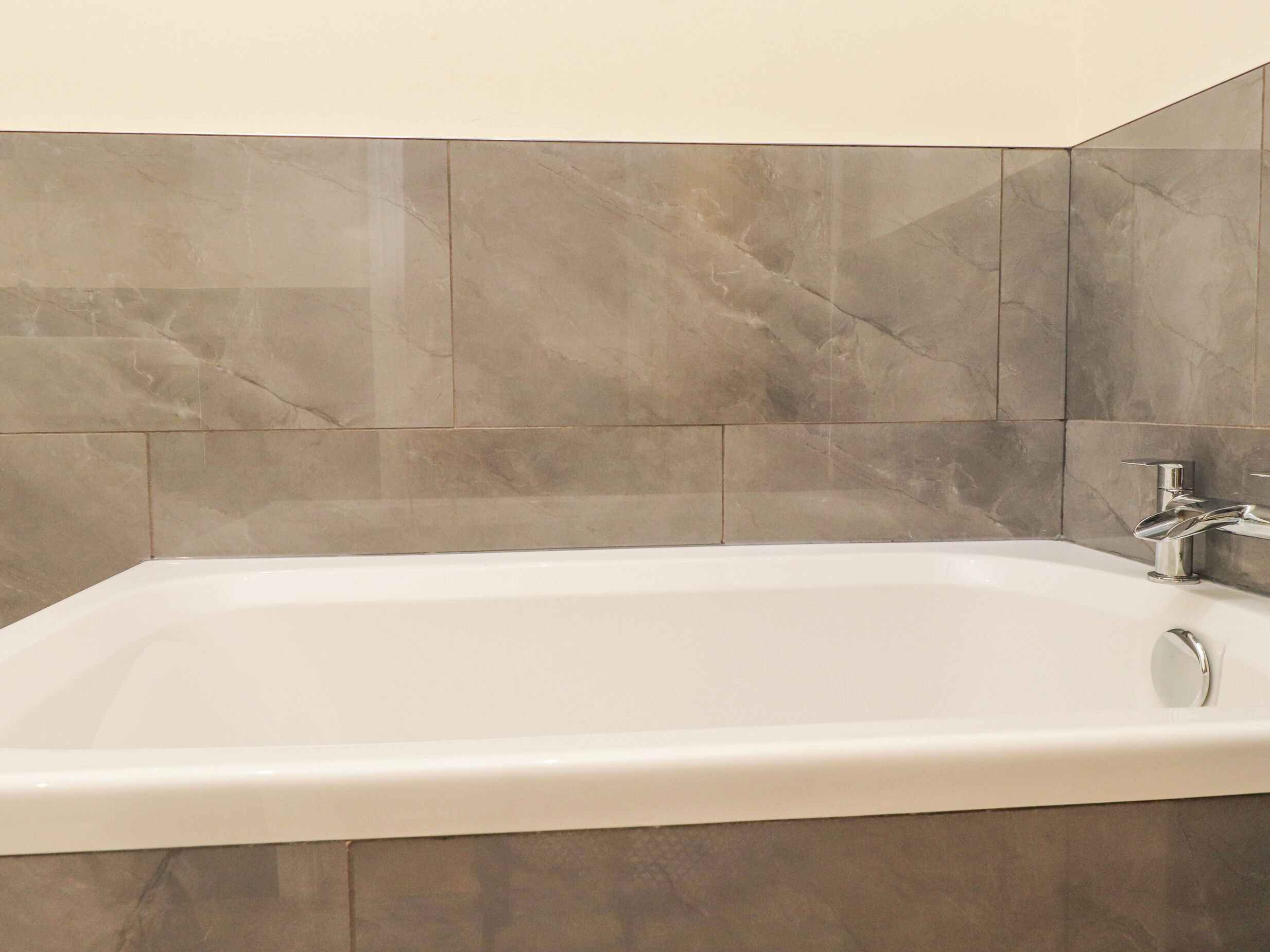 A modern bathroom with a freestanding bathtub, a single faucet, and marble tiles.