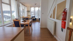 A modern kitchen with wooden countertops, a dining area with a table and chairs, and a view of the city through large windows. - Windows (Ambleside)