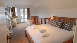 A bedroom with a bed, wooden headboard, bedside tables, a desk, and a chair. - Windows (Ambleside)