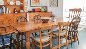 Una mesa de comedor de madera con cuatro sillas, rodeada de armarios y estanterías con diversos objetos.