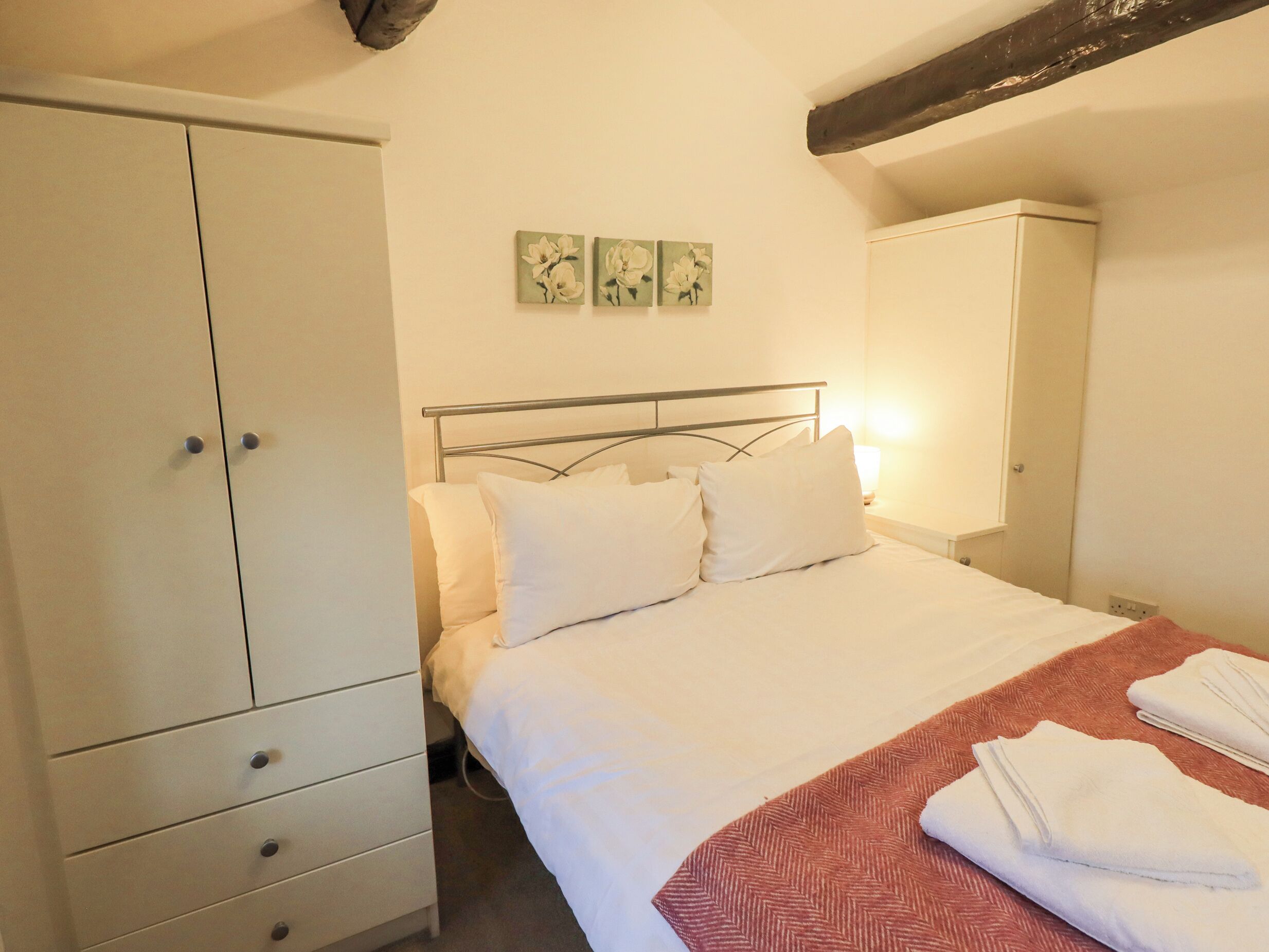 Una camera da letto con un letto, un'armadio bianco e un comodino con una lampada.