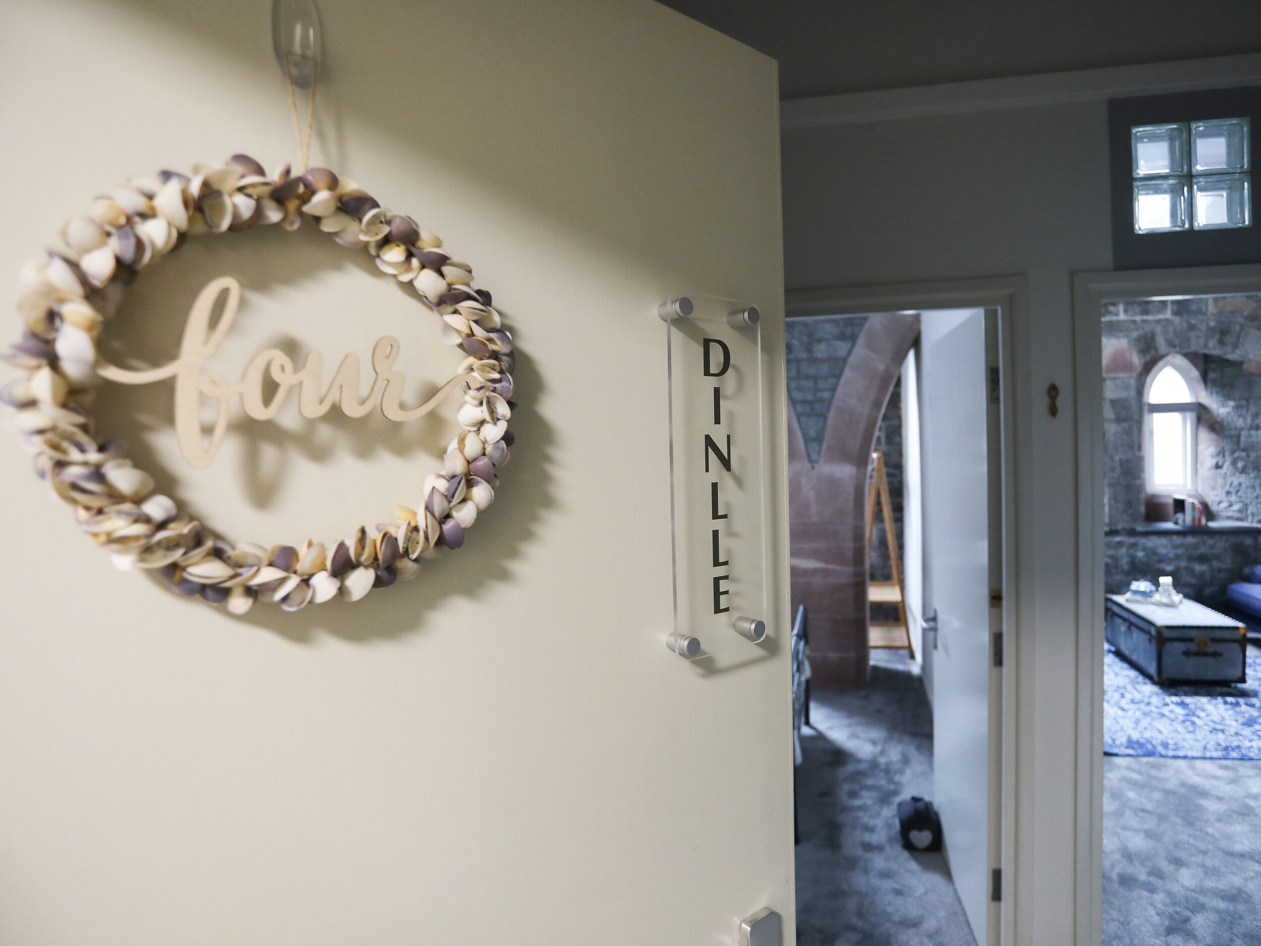 A room with a decorative shell wall hanging and a nameplate reading "DINLE".