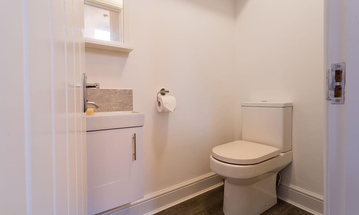A small, clean bathroom with a toilet, sink, and a towel rack.