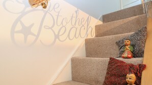 A staircase with a sign reading "Get to the Beach" and decorative pillows. - 21 Florence Road (Lowestoft)