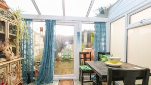 A conservatory with a dining table, chairs, and a view of the garden. - 21 Florence Road (Lowestoft)