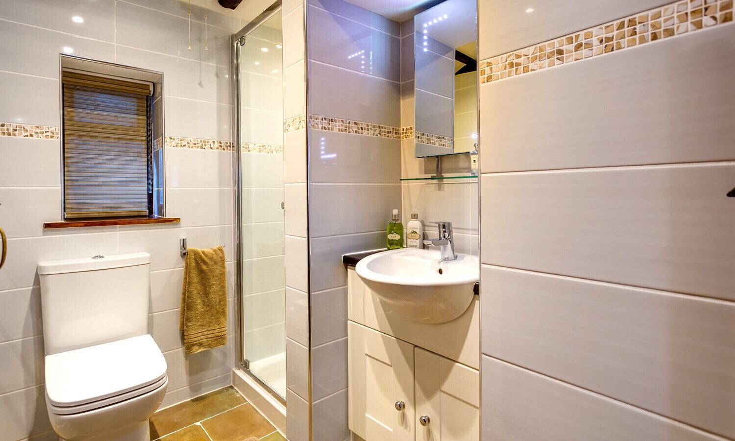 A bathroom with a toilet, a glass shower enclosure, and a sink with a mirror above it.