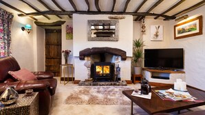 A cozy living room with a stone fireplace, leather sofa, and a flat-screen TV.