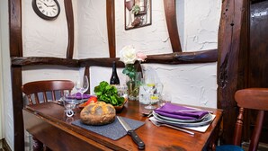 A wooden dining table with a rustic setting, including a clock, a wine bottle, and a rose.