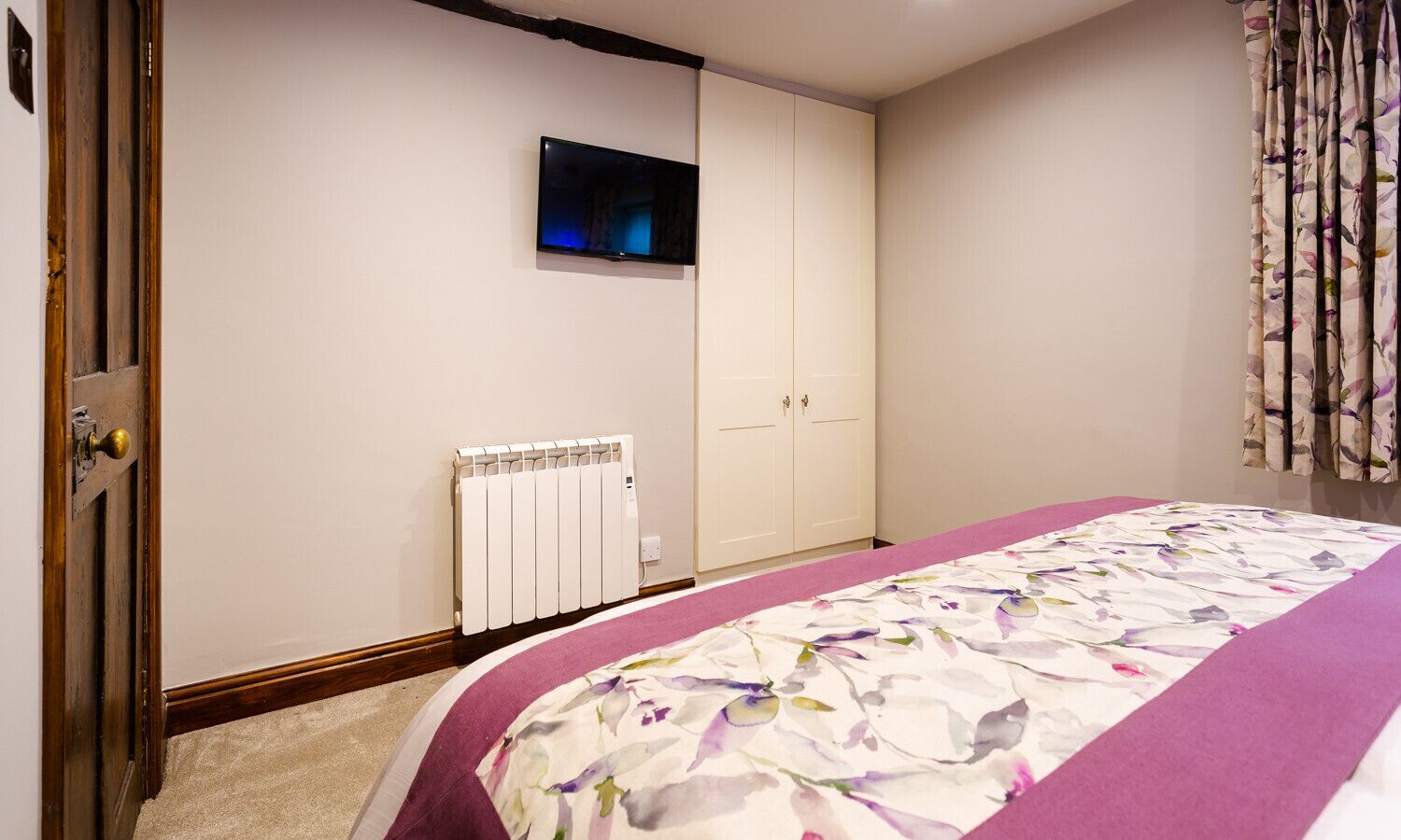 Un dormitorio con cama, radiador, televisor y armario.