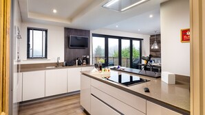 A modern kitchen with a large island, a flat-screen TV, and a view of the outdoors. - Foxrock (Windermere)