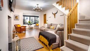 A modern living room with a sofa, a coffee table, a lamp, and a staircase. - Foxrock (Windermere)