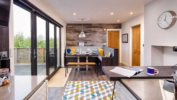 A modern kitchen with a dining area, a bench, and a view of the outdoors. - Foxrock (Windermere)