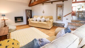 Un salon chaleureux avec un canapé, une cheminée et un escalier menant à une autre pièce.