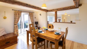 Un comedor con una mesa de madera, sillas y vistas a través de un ventanal.