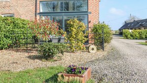 A brick house with a large window, a gravel driveway, and a metal fence. - The Hay Barn (Houghton le Spring)