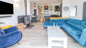 A modern living room with a blue sofa, a white coffee table, and a fireplace. - The Hay Barn (Houghton le Spring)