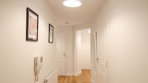 A hallway with white walls, wooden flooring, and framed artwork. - Nautical Breeze (Weymouth)