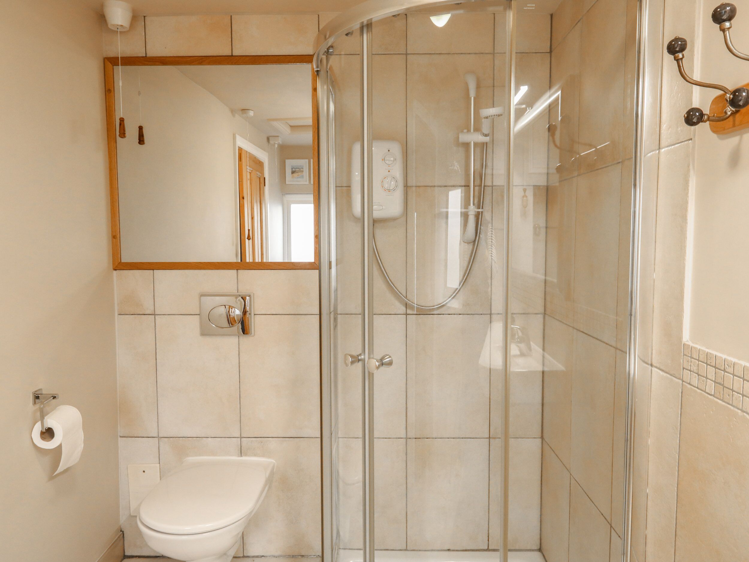 A modern bathroom with a glass-enclosed shower, a toilet, and a mirror.