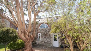 A stone building with a white door and a window with a semi-circular arch. - Little Brook (Weymouth)